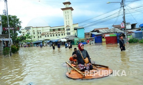 [plustrasi] Warga melintasi Jalan Raya Dayeuhkolot, Kabupaten Bandung yang sudah tergenang banjir akibat luapan Sungai Citarum, Kamis (9/3).