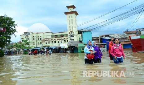 Warga melintasi Jalan Raya Dayeuhkolot, Kabupaten Bandung yang sudah tergenang banjir akibat luapan Sungai Citarum, Kamis (9/3).