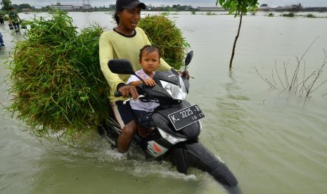 Warga melintasi jalan yang tergenang banjir di Kudus, Jawa Tengah / Ilustrasi 