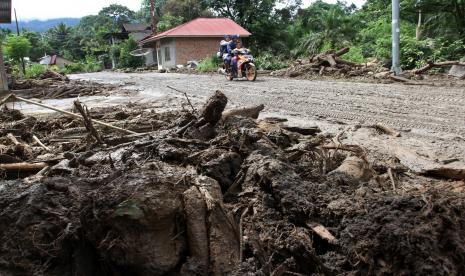 Warga melintasi jalan yang tertutup lumpur luapan Sungai Batang Nango di Kampung Sawah, Nagari Kajai, Kecamatan Talamau, Kabupaten Pasaman Barat, Sumatera Barat, Selasa (1/3/2022). Intensistas hujan yang tinggi mengakibatkan Sungai Batang Nango meluap dengan membawa material longsor seperti lumpur, kayu dan batu. Polisi Tambah Anjing Pelacak Cari Korban Tertimbun Longsor di Pasaman