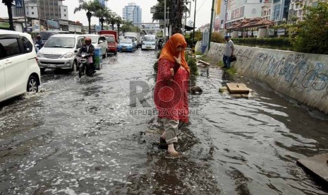  Warga melintasi jalanan yang tergenang air di kawasan Gunung Sahari, Mangga Dua, Jakarta Utara, Jumat (14/12).    (Republika/Adhi Wicaksono)