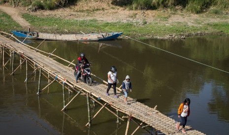 Warga melintasi jembatan bambu di atas Sungai Bengawan Solo yang menghubungkan Desa Mojolaban, Sukoharjo dengan Kampung Sewu di Solo, Jawa Tengah, Rabu (19/6/2019).