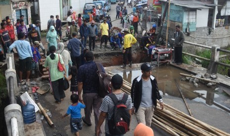 Warga melintasi jembatan darurat akibat amblasnya Jembatan Kali Krukut di Jalan Pitara, Depok, Jawa Barat, Rabu (3/5).