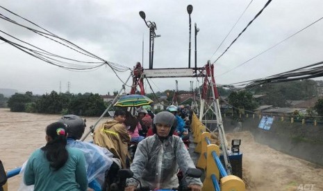 Warga melintasi jembatan di atas Bendung Katulampa, Kecamatan Sindangrasa Bogor Timur, Kota Bogor, Rabu (1/1/2020) pagi. Saat ini Bendung Katulampa berstatus siaga 2 dengan debit 340 meter kubik per detik. 