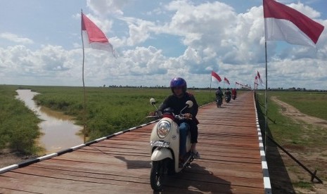 Warga melintasi jembatan penghubung Desa Sebemban dan Desa Melintang di Kecamatan Muara Wis, Kabupaten Kutai Kartanegara, Provinsi Kalimantan Timur pada Selasa (13/11). Jembatan dibangun lewat program TMMD. 