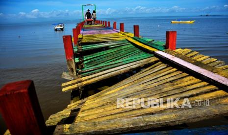 Warga melintasi jembatan yang rusak di kawasan Desa Nelayan Salodong, Biringkanaya, Makassar, Sulawesi Selatan, Jumat (4/2/2022). Jembatan kayu yang menjadi akses nelayan dari sandaran perahu ke pemukiman itu kondisinya rusak sehingga mebahayakan warga yang melintas terutama saat air laut sedang pasang. 