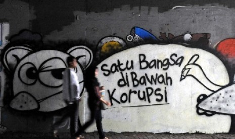 Warga melintasi Mural yang bertuliskan kritik terhadap korupsi.