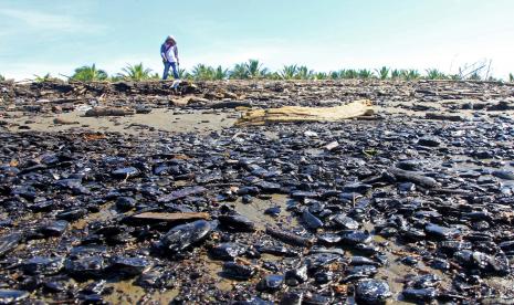 Warga melintasi pantai yang tercemar limbah batu bara.