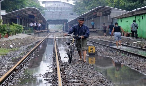 Warga melintasi rel kereta api di Stasiun Sudirman Jakarta Pusat,Kamis (17/1), yang ditutup sementara akibat banjir.  (Republika/Aditya Pradana Putra)