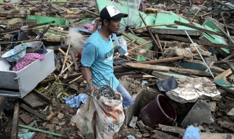 Warga melintasi reruntuhan rumah yang rusak akibat tsunami di Desa Kunjir, Kecamatan Rajabasa, Lampung Selatan, Lampung, Jumat (28/12/2018).