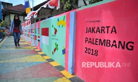 Warga melintasi salah satu bagian kampung yang telah dihiasi dengan warna warni logo Asian Games di Kampung Cempaka Bukit Kecil Palembang,sumsel, Ahad (24/6).