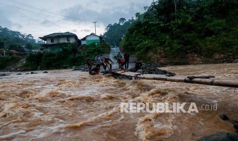 Warga melintasi Ssungai Ciberang menggunakan jembatan swadaya masyarakat di Desa Ciladaheun, Lebak, Banten, Selasa (30/3/2021). Menurut keterangan warga setempat, setahun pascaditerjang bencana banjir bandang jembatan yang merupakan akses jalan nasional tersebut belum dibangun dan tidak bisa dilalui kendaraan ketika hujan deras karena air sungai Ciberang meluap. 