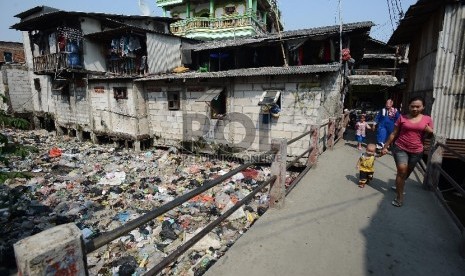 Warga melintasi sungai yang dipenuhi sampah di Muara Baru, Jakarta utara, Selasa (19/5).