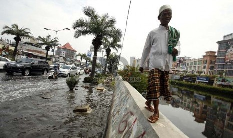  Warga melintasi tanggul kali untuk menghindari jalan yang tergenang air di kawasan Gunung Sahari, Mangga Dua, Jakarta Utara, Jumat (14/12).  (Republika/Adhi Wicaksono)