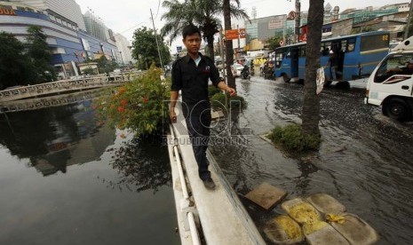  Warga melintasi tanggul kali untuk menghindari jalan yang tergenang air di kawasan Gunung Sahari, Mangga Dua, Jakarta Utara, Jumat (14/12).  (Republika/Adhi Wicaksono)