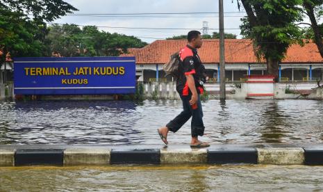 Ilustrasi. Warga melintasi Terminal Tipe A Jati yang tergenang banjir di Kudus, Jawa Tengah, Ahad (7/2/2021). Terminal Induk Jati di Kudus Lumpuh Akibat Banjir