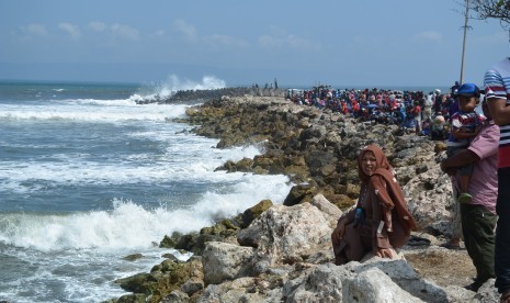 Warga memadati perairan untuk melihat proses evakuasi perahu nelayan karam diterjang ombak di Plawangan Puger, Jember, Jawa Timur, Kamis (19/7).