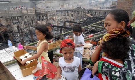  Warga memandangi puing-puing bangunan yang tersisa dari kebakaran yang melanda pemukiman semi permanen di Jalan Kapuk Raya, Kapuk, Jakarta Utara, Selasa (11/12).( Republika/Agung Fatma Putra)