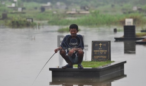 Warga memanfaatkan luapan Kali Pesanggrahan yang merendam Taman Pemakaman Umum (TPU) Tanah Kusir, Jakarta Selatan, Kamis (27/2). Hujan deras yang menguyur Ibu Kota menyebabkan genangan di sejumlah wilayah Jakarta. 