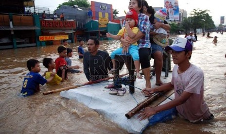   Warga memanfaatkan papan kayu untuk melintasi genangan air banjir yang merendam Jalan KH Abdullah Syafe'i, Kp melayu Besar, Jakarta, Jumat (18/1).  (Republika/Prayogi)