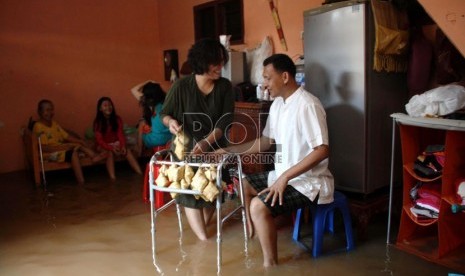  Warga memasak ketupat saat banjir menggenangi rumah mereka di kawasan Bukit Duri, Jakarta, Kamis (8/8). (Republika/ Yasin Habibi)