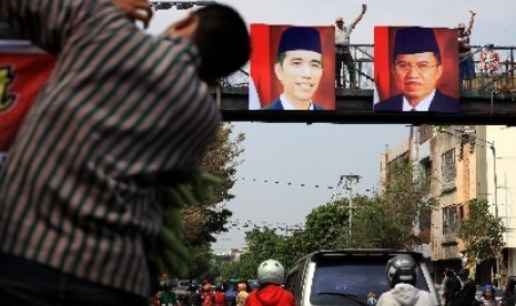 Warga memasang foto Joko Widodo dan Jusuf Kalla di salah satu jembatan penyeberangan di Solo, Kamis (23/10).