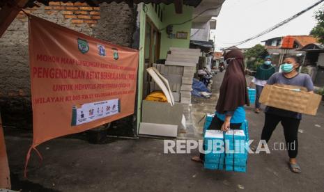 Warga membagikan bantuan makanan dari Dinas Sosial di Kelapa Dua Wetan, Ciracas, Jakarta Timur, Rabu (23/6/2021). Sebanyak 55 orang terkonfrimasi positif COVID-19 yang berasal dari klaster keluarga di dua RT kawasan Kelapa Dua Wetan, Ciracas, Jakarta Timur kini menerapkan Mikro Lockdown untuk mencegah penyebaran COVID-19 di wilayah tersebut. 