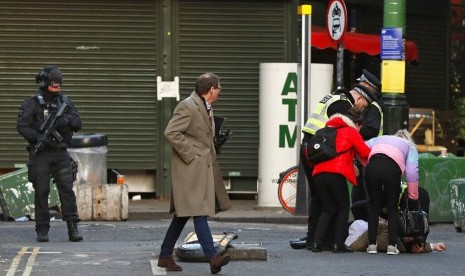 Warga membantu seorang pria yang jatuh saat polisi mengevakuasi masyarakat dari Borough Market di selatan London Bridge di London, Jumat (29/11). Polisi mengatakan sejumlah orang menjadi korban penusukan.