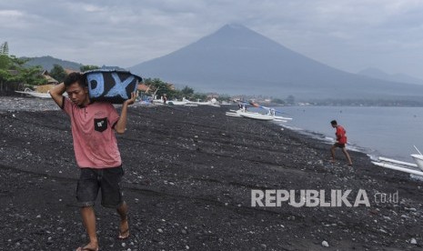 Warga membawa bak berisi ikan yang dibelinya dari nelayan di Pantai Amed dengan latar belakang Gunung Agung, di Karangasem, Bali, Selasa (5/12). 