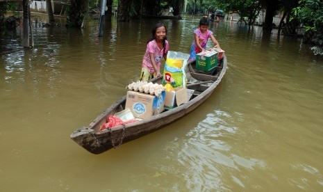 Warga membawa bantuan logistik menggunakan perahu ketika melintas di permukiman yang terendam banjir luapan Sungai Kampar di Desa Buluhcina, Kabupaten Kampar, Riau, Senin (15/2).