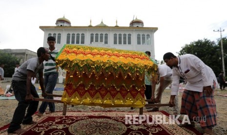 Warga membawa hidangan berbentuk rumah adat yang berisi makanan dari hidang pada kenduri Nuzulul Quran di Masjid Raudhatul Jannah, Desa Pango Raya, Banda Aceh, Aceh, Ahad(19/5/2019).