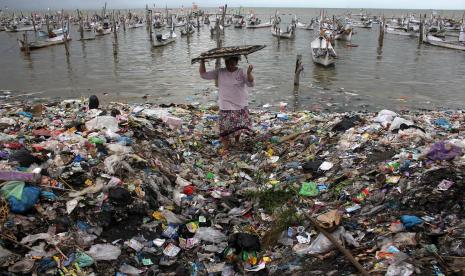 Warga membawa ikan di pantai yang penuh dengan sampah plastik di Desa Kwanyar Barat, Bangkalan, Jawa Timur, Sabtu (21/5/2022).  Indonesia-AS jalin kemitraan untuk mengurangi limbah plastik di laut-laut Indonesia. Ilustrasi.