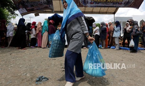 Warga membawa kebutuhan pokok seusai berbelanja di pasar murah (ilustrasi)