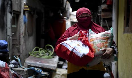 Warga membawa paket bantuan sosial dari pemerintah. 