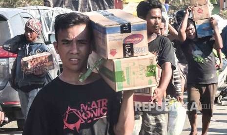 Warga membawa sejumlah barang dari gudang Alfa Midi di Mamboro, Palu Utara, Sulawesi Tengah, Senin (1/10).