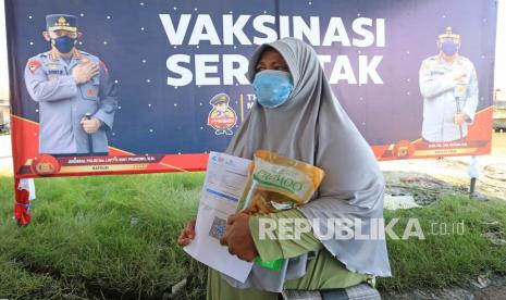 Warga membawa sertifikat vaksin COVID-19 dan minyak goreng kemasan usai mengikuti vaksinasi di Karangsong, Indramayu, Jawa Barat, Senin (14/3/2022). Vaksinasi berhadiah minyak goreng untuk nelayan dan masyarakat pesisir yang digelar Polres Indramayu tersebut guna mendorong percepatan vaksinasi COVID-19.