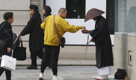 Warga memberi sedekah kepada biksu Budha di pusat perbelanjaan Ginza di Tokyo, Jepang, Rabu (13/11). Bank sentral Jepang menyatakan penggunaan uang kartal di Jepang masih tinggi untuk keperluan sehari-hari.