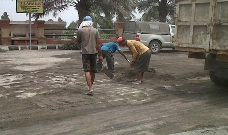   Warga membersihkan pasir hasil erupsi Gunung Kelud di sekitar simpang lima Gumul, Kediri, Sabtu (15/2).