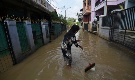 Warga membersihkan sampah saat banjir menggenangi kawasan Cipinang Melayu, Kecamatan Makasar, Jakarta Timur, Minggu (26/2). 