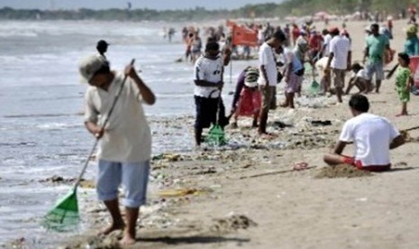 Warga membersihkan sampah yang terdampar dan mengganggu wisatawan di Pantai Kuta, Bali.