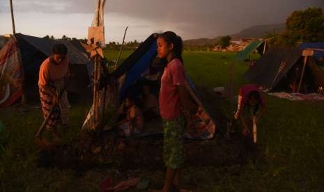 Warga membuat parit di sekililing tenda darurat yang mereka bangun di pematang sawah di Tanjung, Lombok Utara, Jawa Timur, Kamis (9/8).