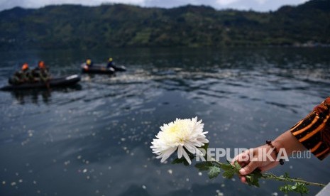 Warga memegang bersiap melemparkan bunga dalam prosesi tabur bunga untuk korban tenggelamnya KM Sinar Bangun di kawasan titik tenggelamnya kapal di Danau Toba, Sumatera Utara, Senin (2/7).