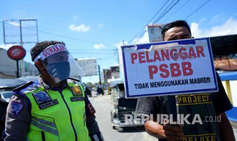 Warga memegang papan pelanggaran saat razia penguatan Pembatasan Sosial Berskala Besar (PSBB) di Kota Gorontalo, Gorontalo, Rabu (27/5/2020). Kegiatan tersebut dilakukan untuk meningkatkan tingkat kedisiplinan masyarakat agar menerapkan protokol kesehatan sebagai upaya pencegahan COVID-19.