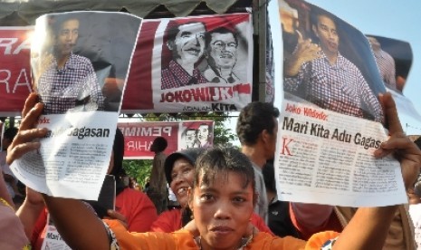 Warga memegang poster bergambar Calon Presiden Joko Widodo