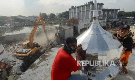  Warga memindahkan kubah masjid saat penertiban yang dilakukan di Pasar Ikan Penjaringan, Jakarta Utara, Senin (11/4). (Republika/Raisan Al Farisi)