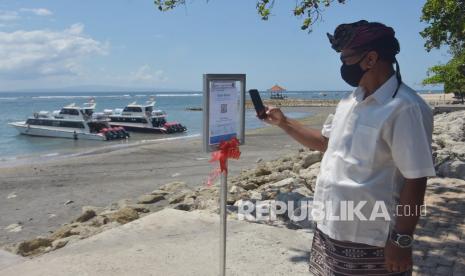 Warga memindai kode batang sertifikat vaksin COVID-19 menggunakan aplikasi PeduliLindungi saat berkunjung di Pantai Sanur, Denpasar, Bali, Kamis (30/9/2021). Penerapan aplikasi PeduliLindungi di objek wisata yang dicanangkan sebagai kawasan zona hijau bebas COVID-19 tersebut untuk menjaga kesehatan masyarakat yang akan berdampak positif bagi pemulihan ekonomi di tempat pariwisata Sanur serta sebagai upaya menekan penyebaran COVID-19. 