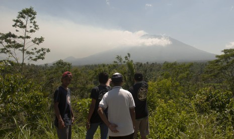 Warga memotret asap yang mulai mengepul dari kawah Gunung Agung dari Pos Pemantauan Desa Rendang, Karangasem, Bali, Selasa (19/9). 