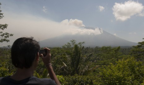 Warga memotret asap yang mulai mengepul dari kawah Gunung Agung dari Pos Pemantauan Desa Rendang, Karangasem, Bali, Selasa (19/9). 