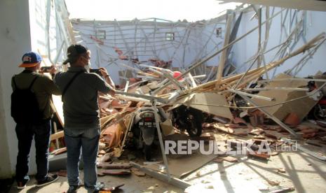 Warga memotret atap rumah yang ambruk akibat gempa bumi di Mamuju, Sulawesi Barat, Kamis (14/1/2021). BMKG Sulawesi Barat mencatat gempa bumi berkekuatan 5,9 skala richter terjadi pada pukul 14:35:49 WITA di empat kilometer Barat Laut Majene-Sulbar dengan kedalaman 10 Km dan tidak berpotensi tsunami. 