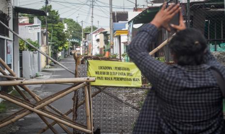 Warga memotret papan pemberitahuan karatina wilayah di Kampung Wonosaren RW VIII, Jagalan, Solo, Jawa Tengah, Kamis (1/7/2021). Satuan Tugas (Satgas) Penanganan COVID-19 kelurahan setempat memberlakukan karantina wilayah akibat ditemukan 40 warga terkonfirmasi positif COVID-19 dari klaster keluarga dan klaster wisata. 